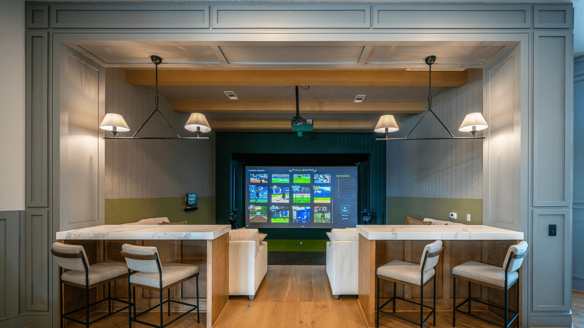 Indoor golf simulator room with seating area.