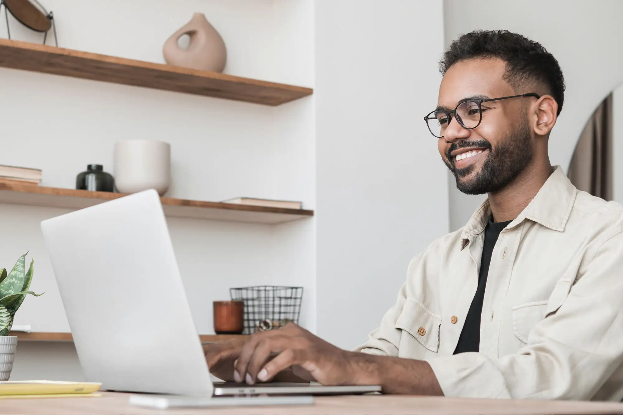 Person typing on laptop, smiling.