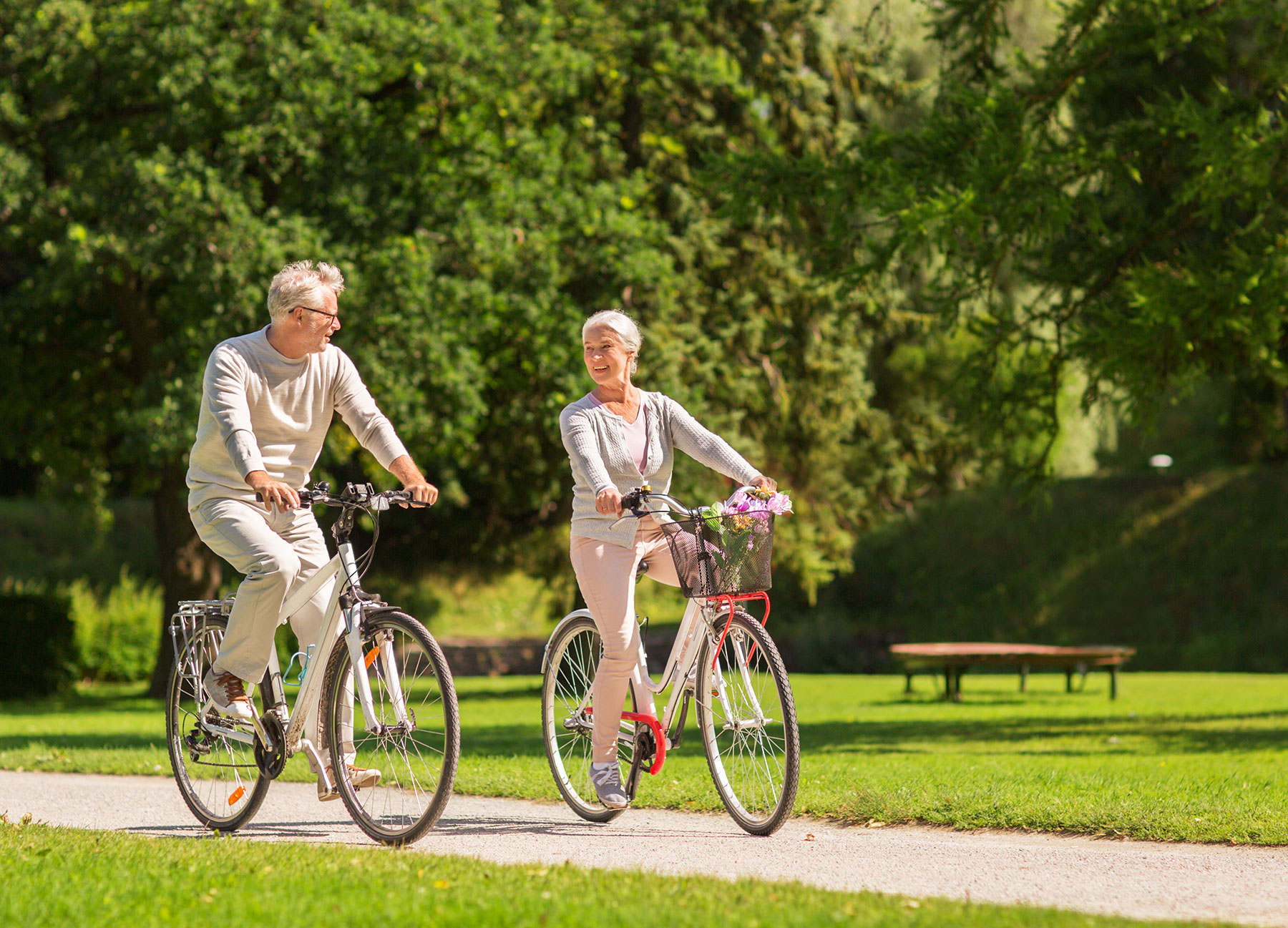 A senior couple riding bicycles on a path through a park