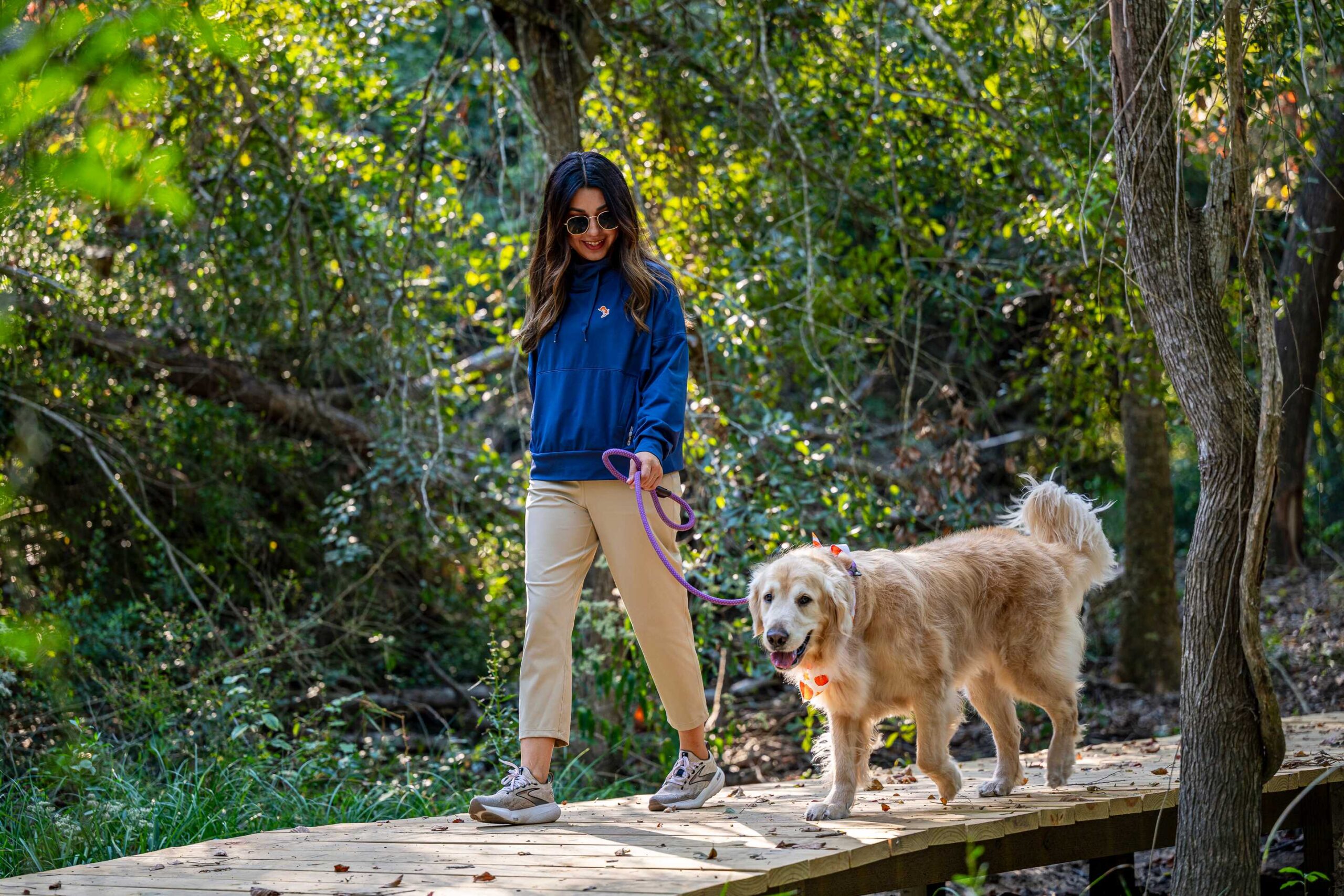Girl walking dog on trail with trees and walkway